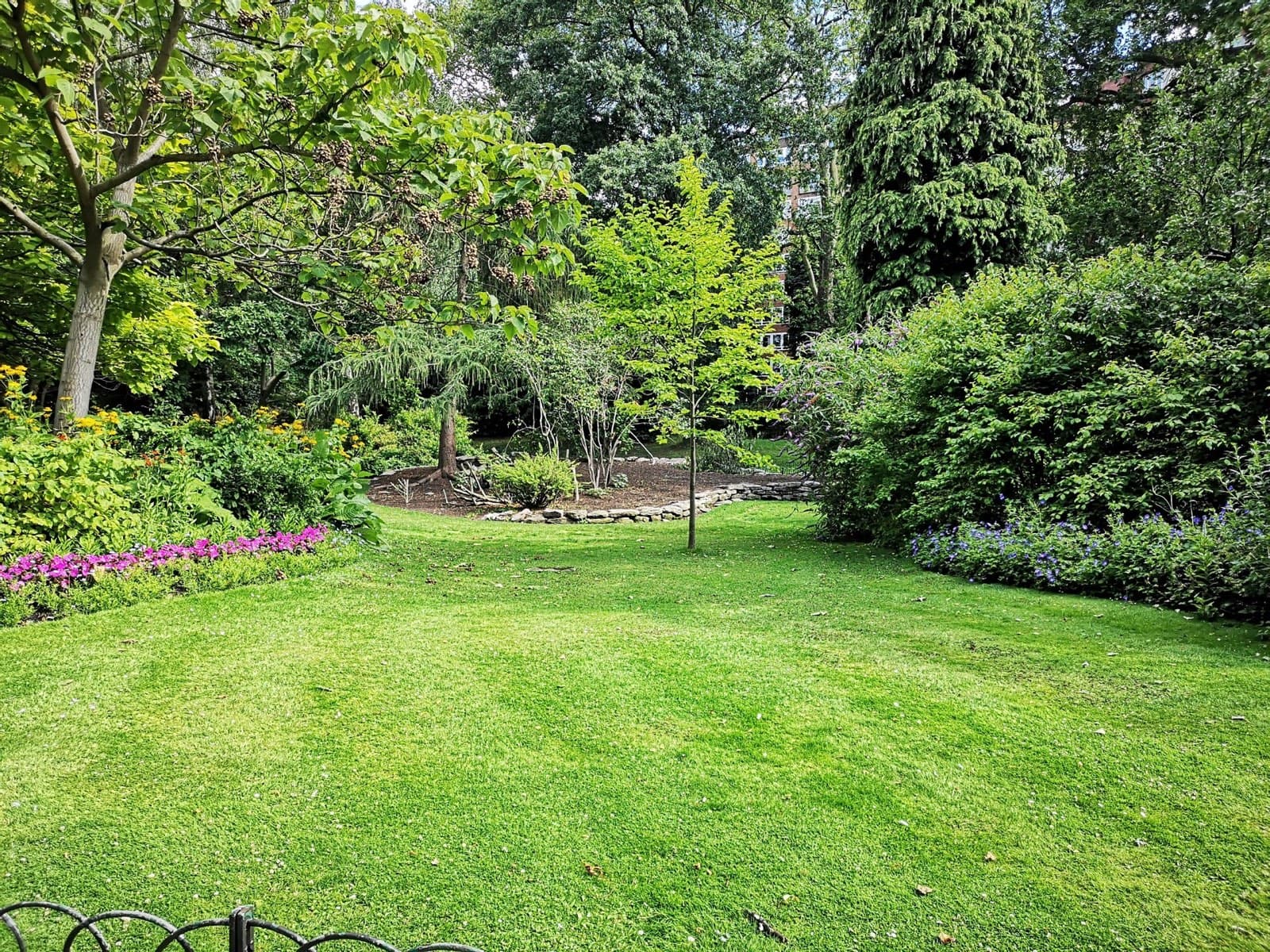 Manicured South Jersey backyard bordered by dense trees and garden beds — a mosquito-prone outdoor living space